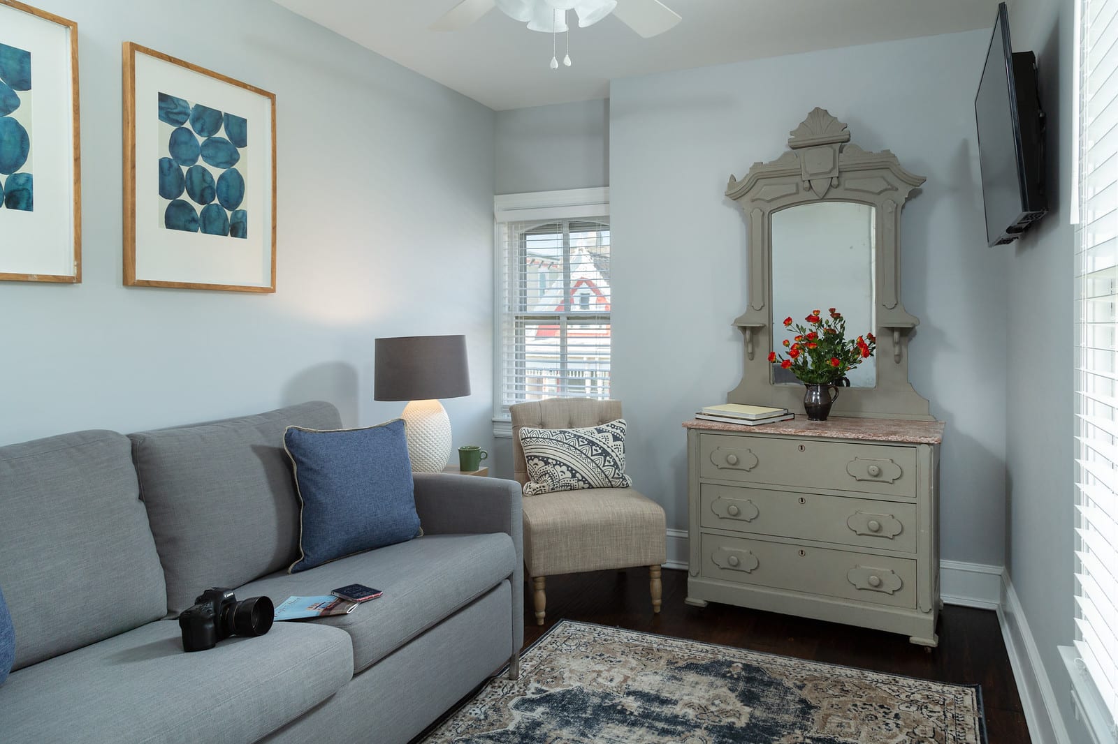 Pale blue guest room with sofa, chair and dresser.