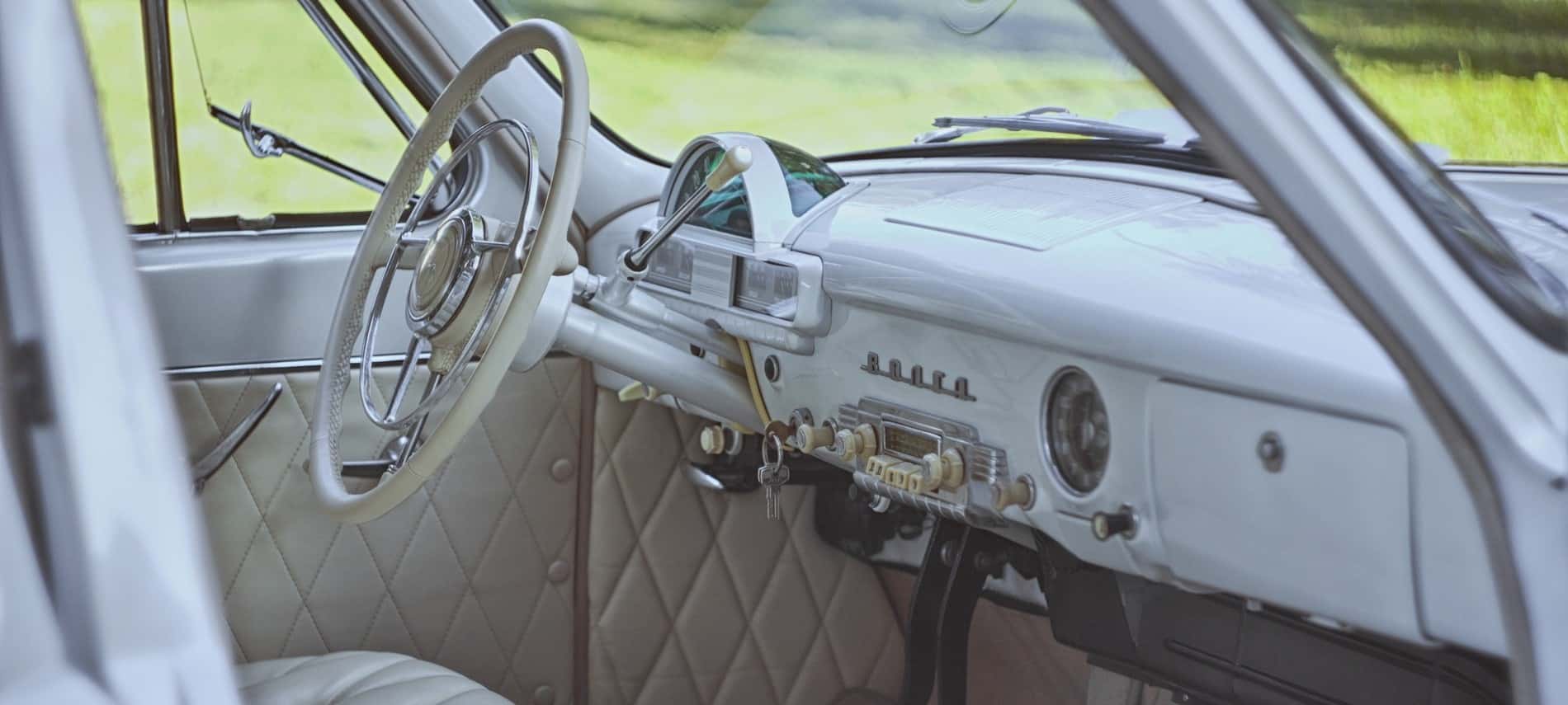 Inside of a classic vintage car showing a white interior in mint condition