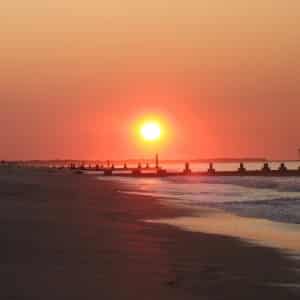 Gorgeous sunrise at a seashore with waves lapping and orange and yellow skies