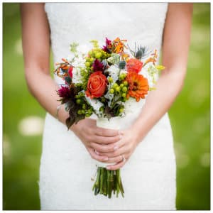 Beautiful bride in a white dress against a green background holding a bouquet with a white ribbon