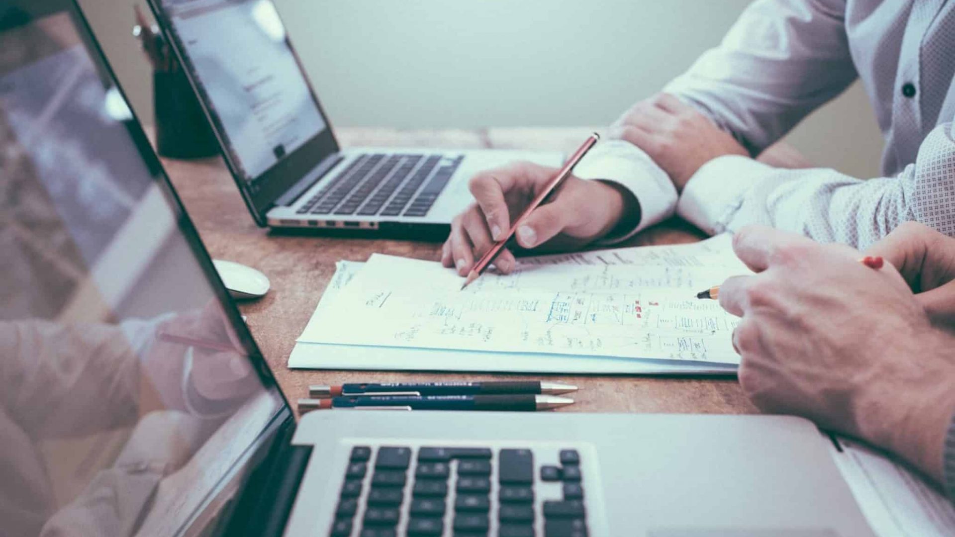 People working at a desk with paper and laptops