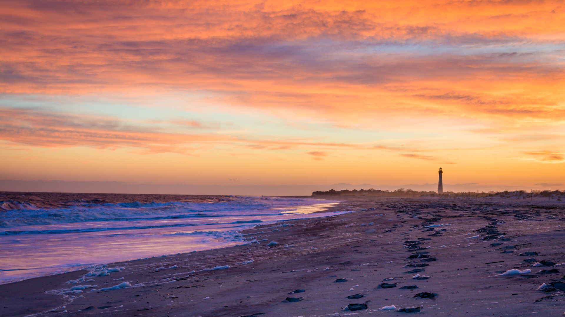 Cape May beach at sunset with lighthouse in background