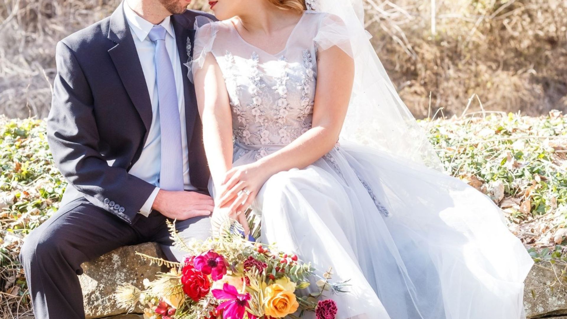 wedding couple kissing on beach with bouquet in front of them