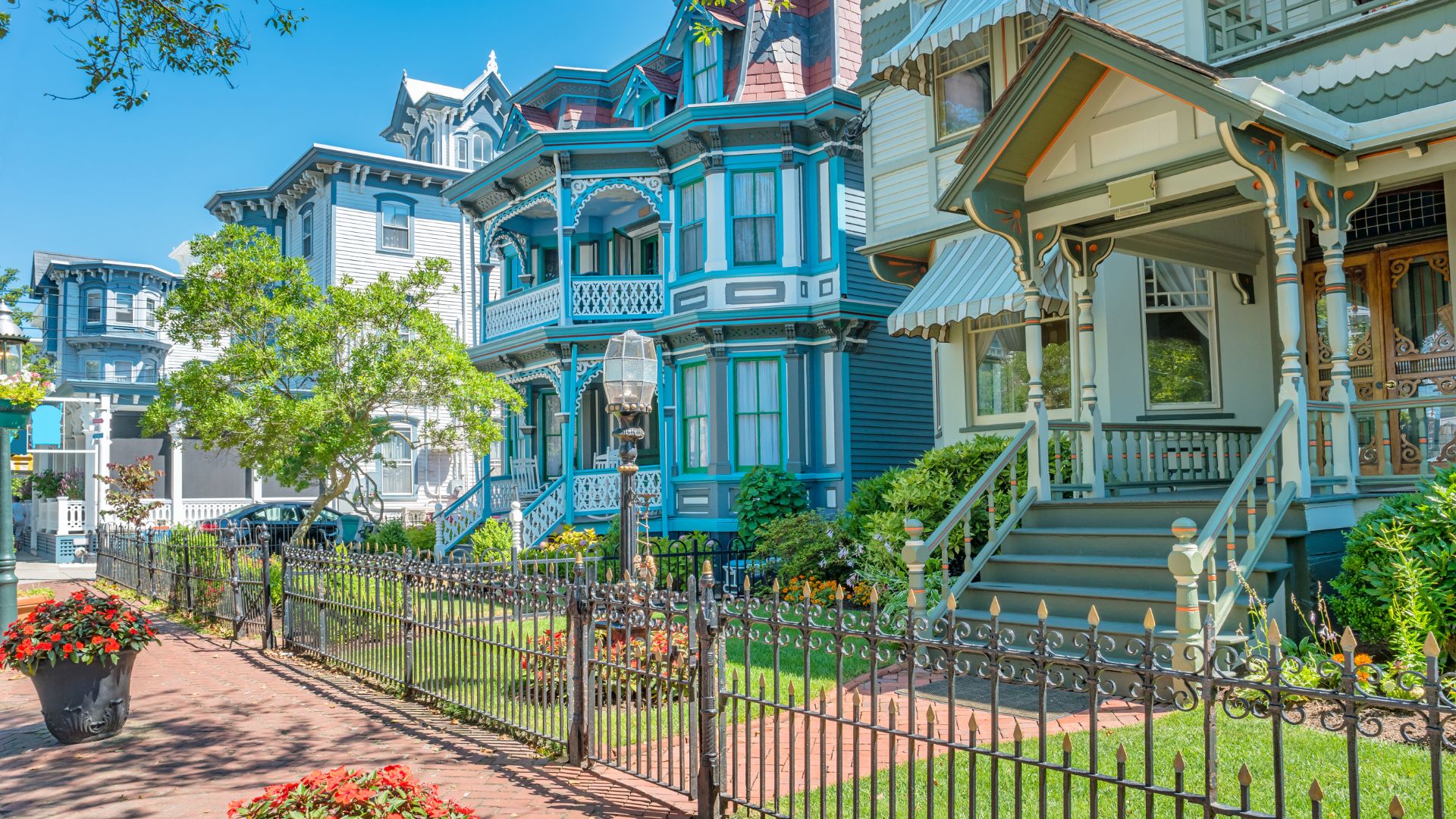 Row of brightly colored Victorian houses on street with flower pots, fence