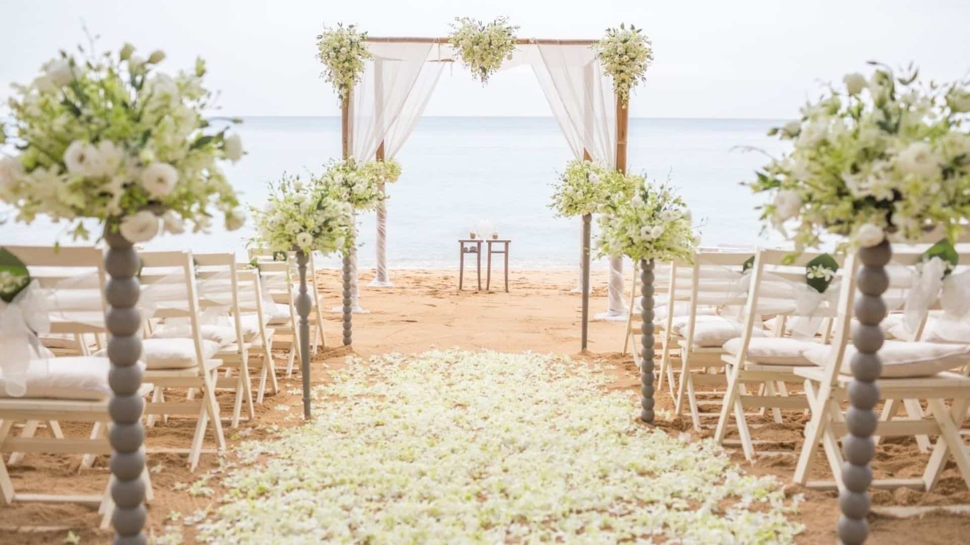 Scene of beach wedding with arbor and chairs