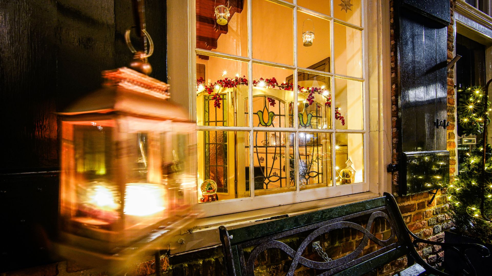  View inside shop window with vintage stained glass panels, old-fashioned light outdoors, and metal bench