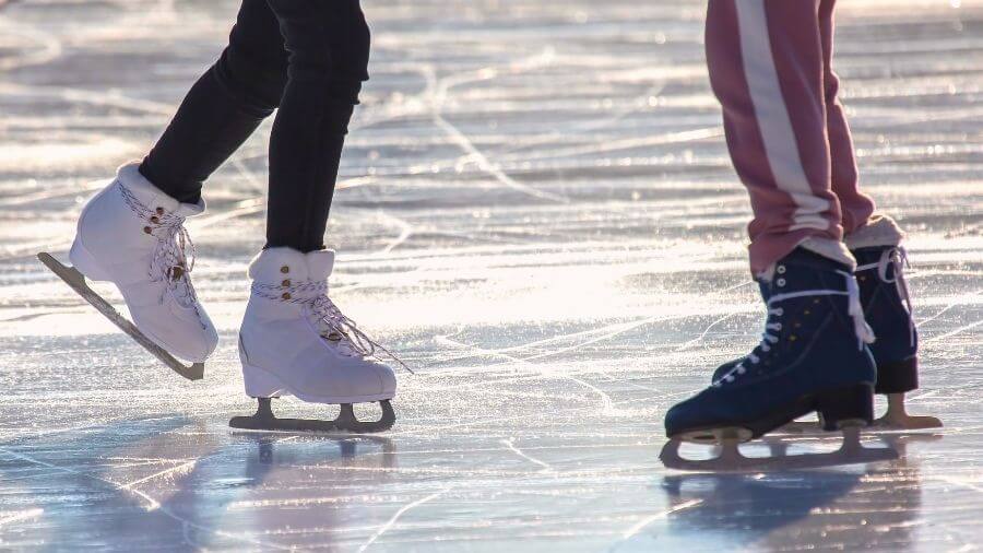 close up of the feet of an ice skating couple enjoying outdoor rink