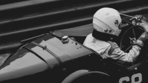a racer wearing a helmet driving a vintage f1 car