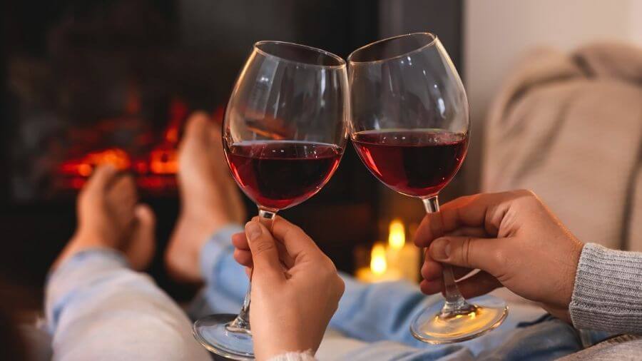 couple relaxing with glasses of wine in front of a cozy fireplace