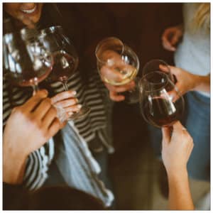 Several ladies standing in a group holding glasses of red wine 