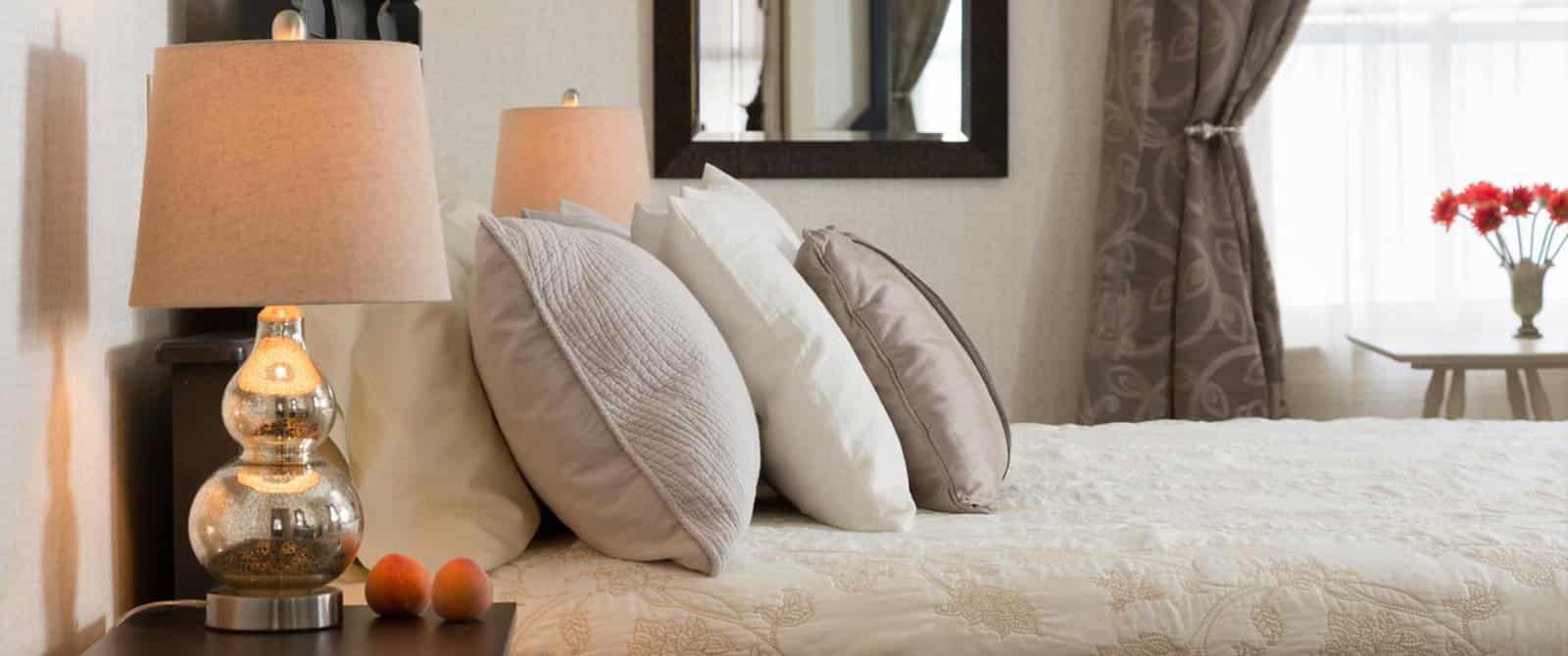 Bedroom with dark wooden ornate headboard, cream-colored bedding, and dark wooden nightstand