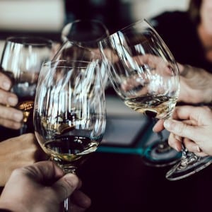 Group of hands holding clear glasses with wine together in a circle