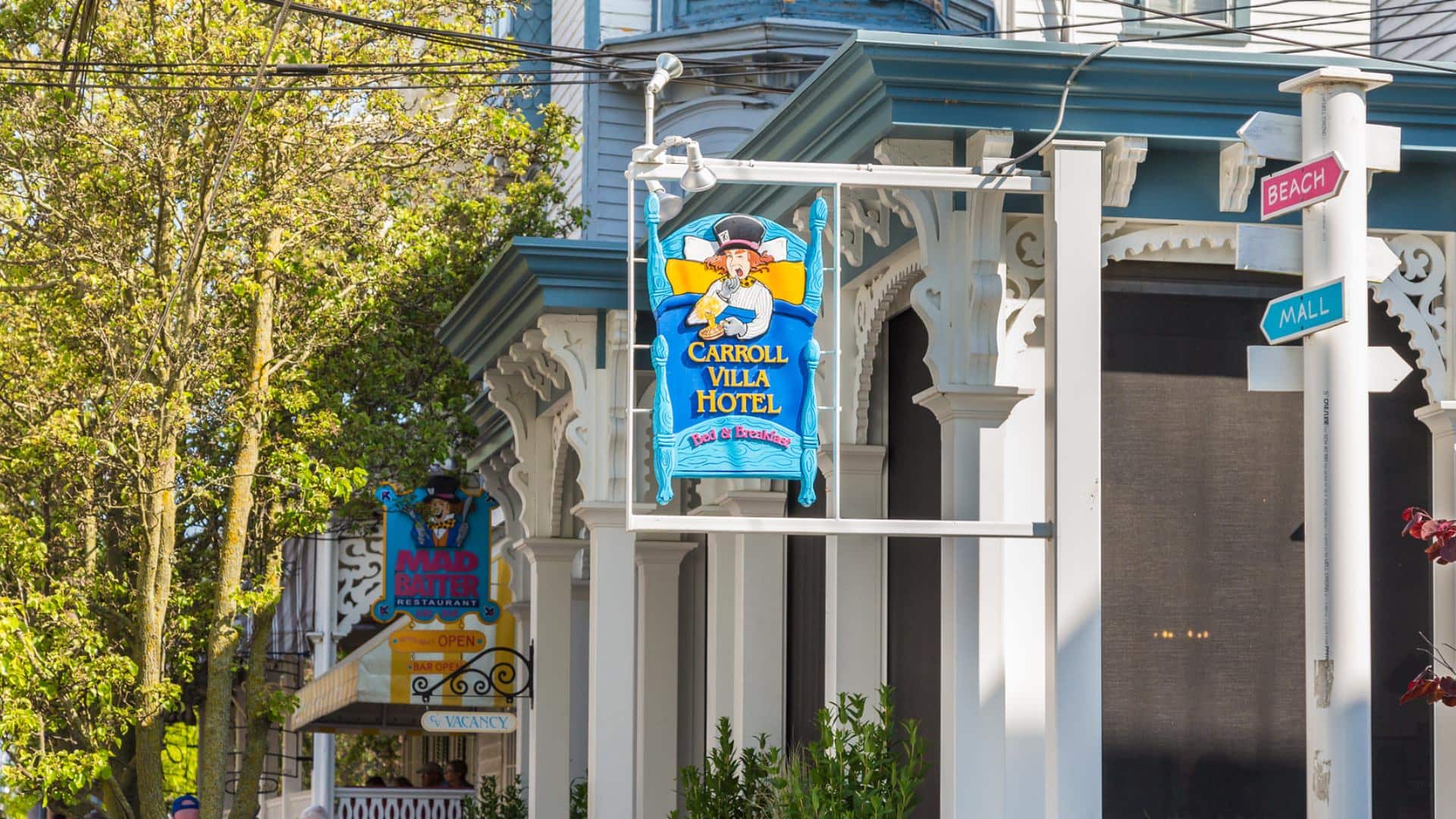 Close up view of the Carroll Villa Hotel and Mad Batter Restaurant signs on the outside of the exterior of the property surrounded by green trees