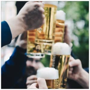 Several glasses of light beer being raised in a toast - image by quentin dr unsplash.com