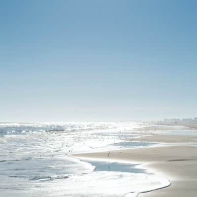 Stunning shoreline with soft waves lapping a wide open beach and blue skies overhead