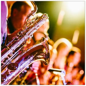 A group of musicians on a stage under lights playing saxophones