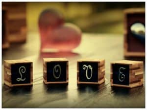 Four wooden blocks with black and silver letters that spell out the word LOVE